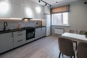 a kitchen with white cabinets and a table with chairs at ЖК Sun city in Oral