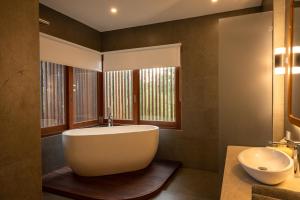 a bathroom with a large tub and a sink at Villa Suarga Des Anicca in Ubud