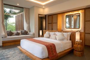 a bedroom with a large bed and a couch at Villa Suarga Des Anicca in Ubud