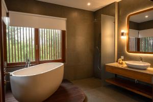 a bathroom with a tub and a sink and a mirror at Villa Suarga Des Anicca in Ubud