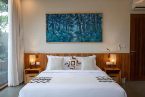 a bedroom with a bed with two lamps and a painting at Villa Suarga Des Anicca in Ubud