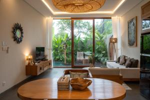 a living room with a table and a large window at Villa Suarga Des Anicca in Ubud