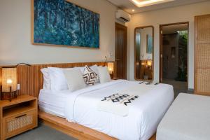 a bedroom with a large white bed and a mirror at Villa Suarga Des Anicca in Ubud