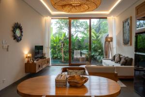 a living room with a table and a large window at Villa Suarga Des Anicca in Ubud