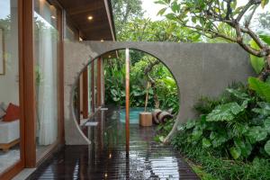 an archway leading into a house with a garden at Villa Suarga Des Anicca in Ubud