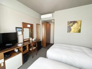 a hotel room with a bed and a desk with a television at Hotel Route-Inn Iwata Inter in Iwata