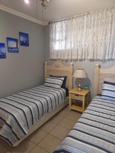 a bedroom with two beds and a table with a lamp at Ocean View Family Apartment - L'Escalier 208 a ABR3 Haven in Amanzimtoti +31 photos