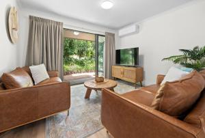 ein Wohnzimmer mit zwei Sofas und einem Fernseher in der Unterkunft Modern & Stylish 2 Bedroom Townhouse in Noosaville