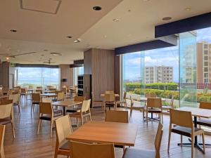 沖縄市にあるオキナワ　グランメールリゾートのテーブルと椅子、大きな窓のあるレストラン
