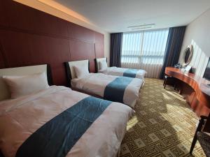 a hotel room with two beds and a desk at Sun Valley Hotel in Yeoju