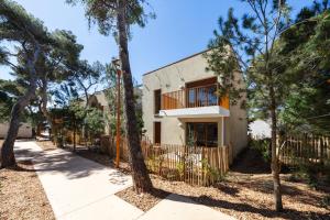 ein Haus mit einem Zaun und Bäumen davor in der Unterkunft La Corniche Bleue in Sausset-les-Pins