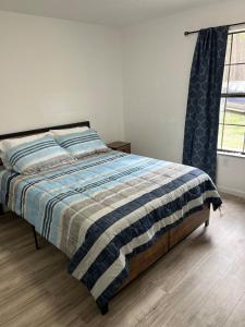 a bedroom with a bed with a striped blanket and a window at House in Malvern, AR in Malvern