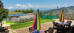 two tables and chairs with umbrellas next to a pool at Orchard Green Dummi in Nāldera