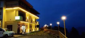 a building with a car parked outside of it at night at Orchard Green Dummi in Nāldera