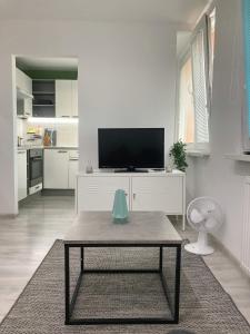 a white living room with a table and a tv at Luxusný apartmán v centre Vrútok in Vrútky