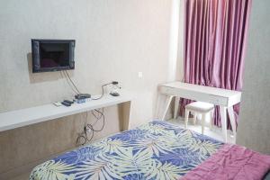 a room with a bed and a desk and a television at Barsa City Babarsari 266 in Yogyakarta