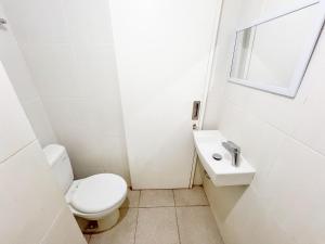 a white bathroom with a toilet and a sink at Barsa City Babarsari 266 in Yogyakarta