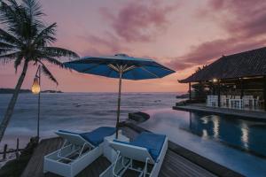 een zwembad met stoelen en een parasol en de oceaan bij Lembongan Seaview in Nusa Lembongan