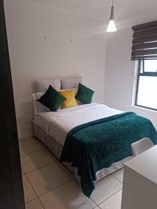 1 dormitorio con 1 cama con almohadas verdes y amarillas en Southside Nest, en Johannesburgo