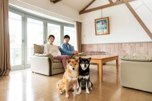 two people and two dogs sitting in a living room at Wan Wan Paradise Izukogen in Ito