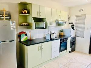 a kitchen with white cabinets and a refrigerator at Palms Beach Apartment- Seaviews in Port Alfred