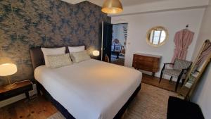 a bedroom with a large white bed and a chair at La maison du Mont Saint Michel in Pontorson