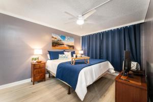 a bedroom with a bed with blue sheets and a tv at Beautiful Oceanview, Great Location Across the Beach in Wailea +23 photos