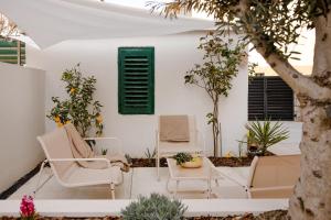 a patio with white chairs and a green shutter at Olea Premium Rooms in Zadar