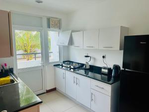 a kitchen with white cabinets and a black refrigerator at Dreamwave Escape Nilaveli in Nilaveli