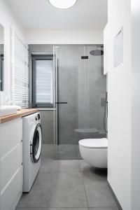 a bathroom with a toilet sink and a washing machine at Apartament Moon by Rentoom Aparthotels in Toruń +22 photos