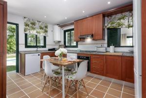 Una cocina con una mesa de madera y sillas blancas. en Villa Bali, en Manilva