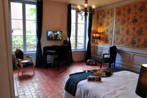 a bedroom with a bed and a desk and windows at Les Glycines Vézelay in Vézelay