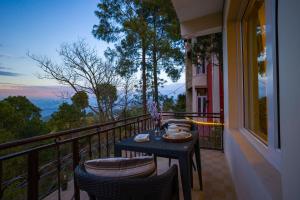 a table and chairs on a balcony with a view at Alaya Stays Captains Nest 3 BHK Retreat With Garden & Scenic Views in Kasauli