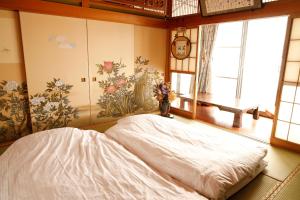 にあるつるのやどの窓のある部屋に白いベッドが置かれた寝室
