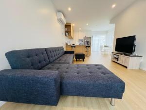 a living room with a blue couch and a television at Central Modern 3-Bedroom,3- Bathroom House with Patio and Carpark- Lower Hutt City Centre in Lower Hutt +46 photos