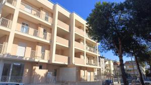 un grand immeuble avec un arbre en face dans l'établissement GIALE MARE Apartments, à Grottammare