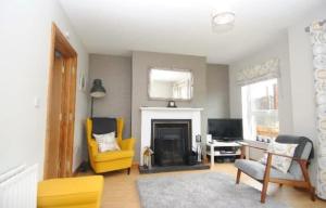 a living room with yellow chairs and a fireplace at Causeway Coastal Terrace Holiday Home portstewart in Portstewart +4 photos