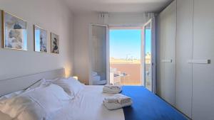 une chambre blanche avec un lit avec des serviettes dessus dans l'établissement GIALE MARE Apartments, à Grottammare