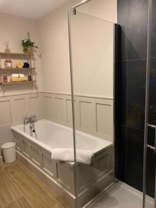 a bath tub with a glass shower in a bathroom at Causeway Coastal Terrace Holiday Home portstewart in Portstewart