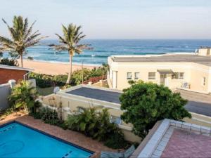 a house with a swimming pool next to a beach at At Doms B&B in Ballito