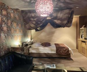 a bedroom with a bed and a couch and a chandelier at HOTEL TWO in ONE Hiroshima-AdultOnly in Hiroshima +1 photo