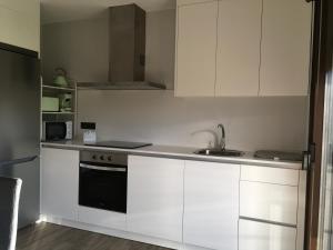 a kitchen with white cabinets and a sink at Rincón do Seves in Tomiño