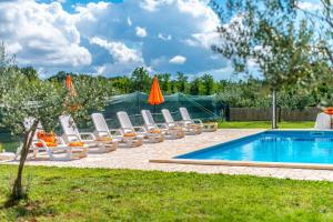 eine Gruppe von Liegestühlen und ein Swimmingpool in der Unterkunft Villa Roza by Kompas Villas in Vošteni