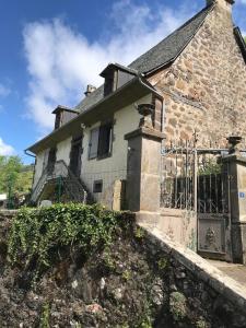 an old stone house with a fence in front of it at La ferme du Liaumiers in Saint-Cirgues-de-Jordanne