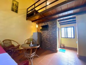 a living room with a table and a refrigerator at Derm Svay Guesthouse - yoga & cafe in Kampot
