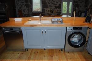 a kitchen with a sink and a washing machine at La ferme du Liaumiers in Saint-Cirgues-de-Jordanne