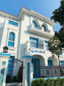 un bâtiment blanc avec des fenêtres bleues et une clôture dans l'établissement Chuỗi Villa Sun Feria 4 Ngủ OCE - Bể Bơi - Gần Biển - Trung tâm Bãi Cháy, à Hạ Long