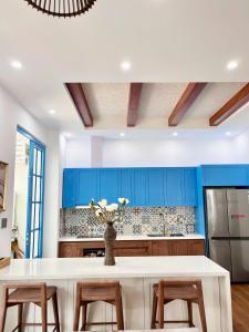 une cuisine avec une table blanche et des armoires bleues dans l'établissement Chuỗi Villa Sun Feria 4 Ngủ OCE - Bể Bơi - Gần Biển - Trung tâm Bãi Cháy, à Hạ Long 5 autres photos