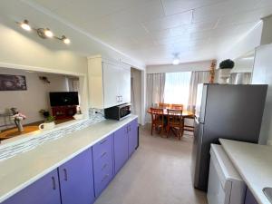 cocina con armarios morados y comedor en Rotorua Holiday Home - Prime Location - With Garden, en Rotorua