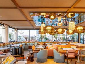 a restaurant with tables and chairs and chandeliers at Mercure Villeneuve Loubet Plage in Villeneuve-Loubet